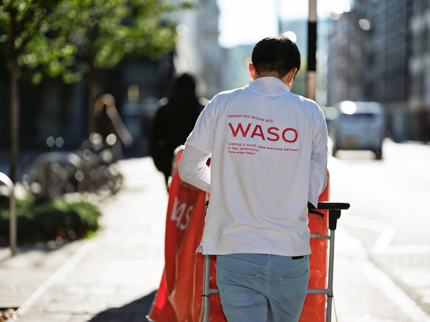 Delivery staff walking with a red trolley on a London street